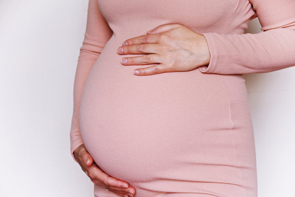 Schwangere Frau hält Hände auf Babybauch